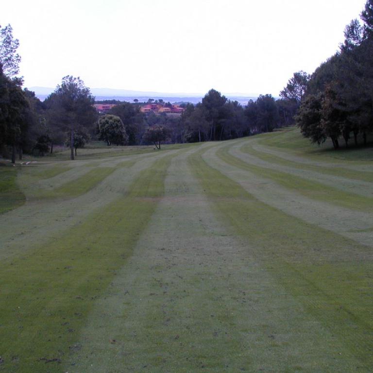 Eine weite Golfplatz-Fairway, flankiert von Bäumen und mit Blick auf das Tal im Hintergrund.