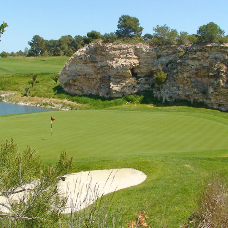 Ein Golfplatz mit einer steilen Felsformation im Hintergrund.