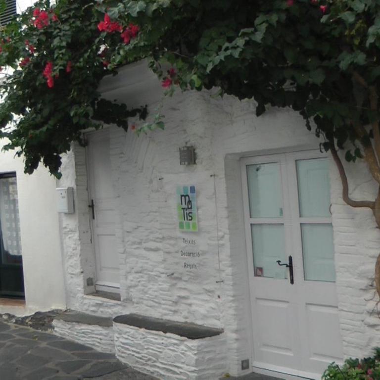 Die weiße Fassade eines Gebäudes, die von grünen Ranken und roten Blumen bewachsen ist.