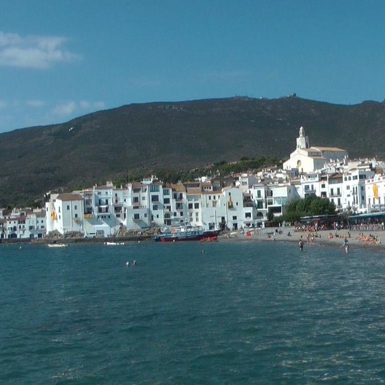 Küstenansicht eines weißen Küstendorfes mit Blick auf das Meer und einen großen Berg im Hintergrund.