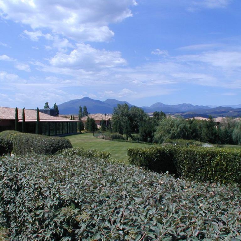 Panoramablick auf ein Anwesen mit Garten und Bergen unter blauem Himmel