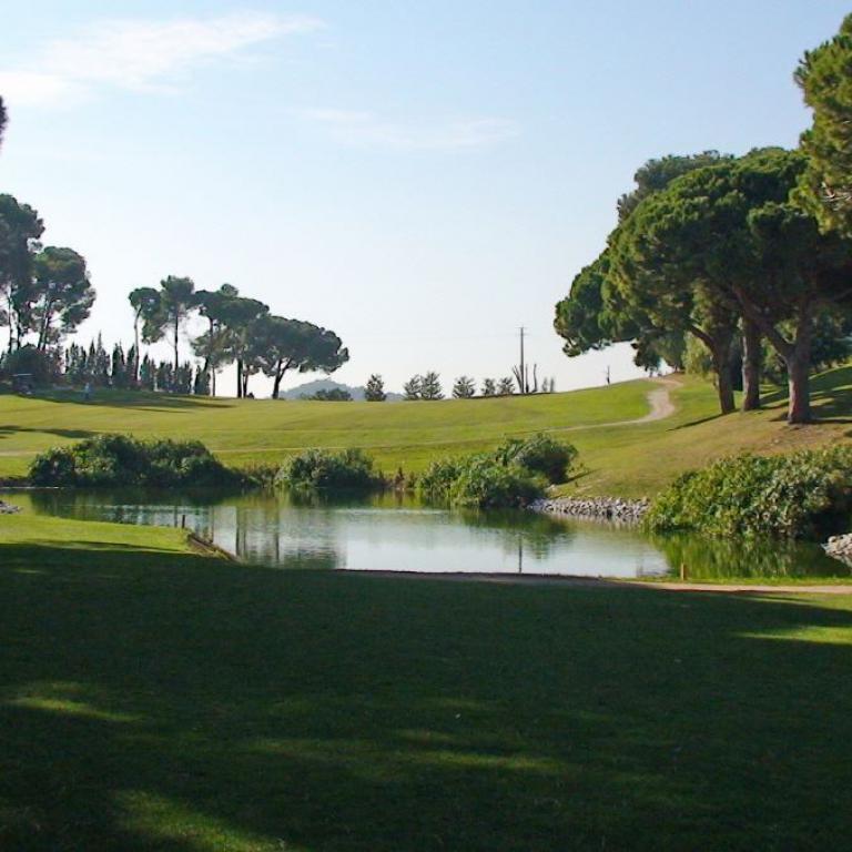 Ein weitläufiger Golfplatz mit einem Wasserlauf und einem kleinen Bach durchzogen.