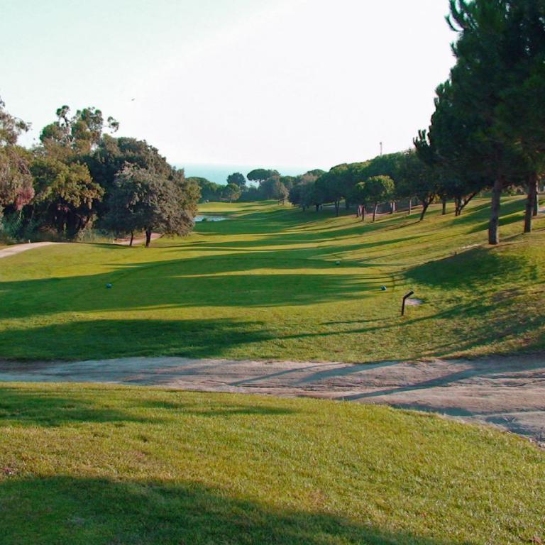 Panoramablick über einen gepflegten Golfplatz mit Blick auf das Meer und Bäume.