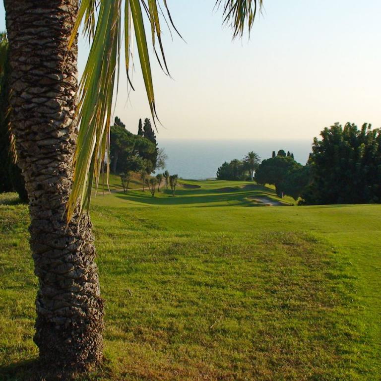 Panoramablick von einem Golfplatz, der sanft zum Meer hin abfällt.