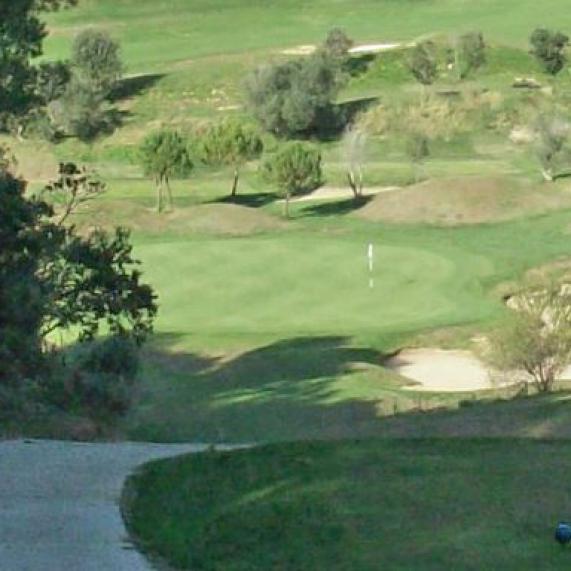 Eine weite Golfplatzlandschaft mit einem Weg im Vordergrund und weitläufigem grünem Spielfeld.