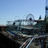 Ein großer Vergnügungspark mit mehreren Fahrgeschäften, einschließlich Achterbahnen und einem Riesenrad, unter blauem Himmel.