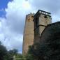 Ein historischer Turm und angrenzende Gebäude unter einem blauen Himmel mit weißen Wolken.