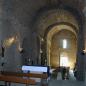 Innenraum einer historischen Kirche mit massiven Steinbögen und Kirchenbänken.