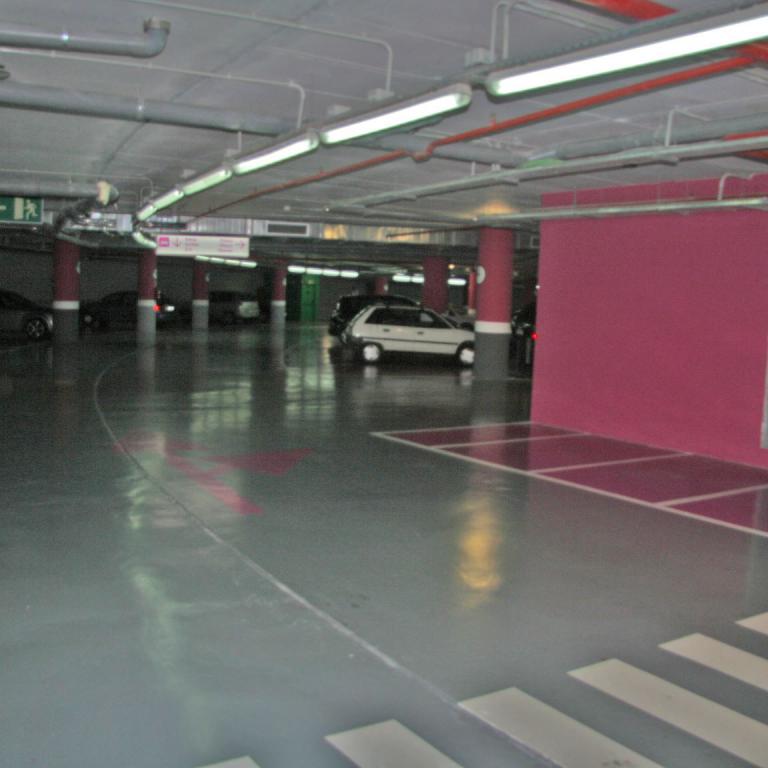 Parkdeck mit beleuchteten Parkplätzen und pinken Säulen.
