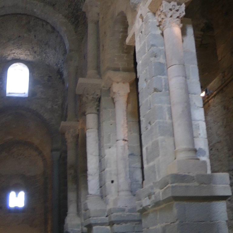 Innenansicht monumentaler Steinbögen und Säulen in einem historischen Kirchengebäude.