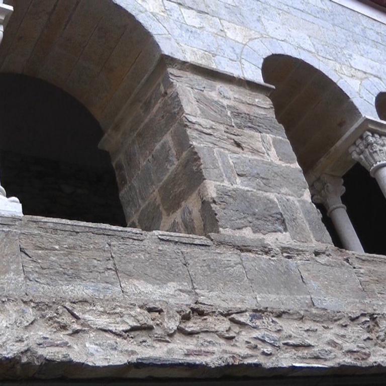 Innenansicht architektonischer Rundbögen und Säulen aus grobem Naturstein.