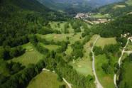 Luftaufnahme einer grünen Berglandschaft mit einem Golfplatz und einem Dorf im Tal.